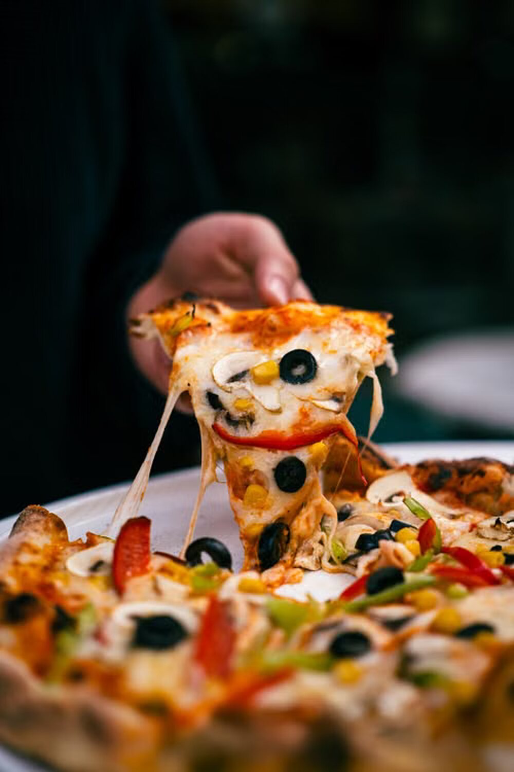 Felie de pizza ridicată de pe tavă, cu mozzarella care se întinde